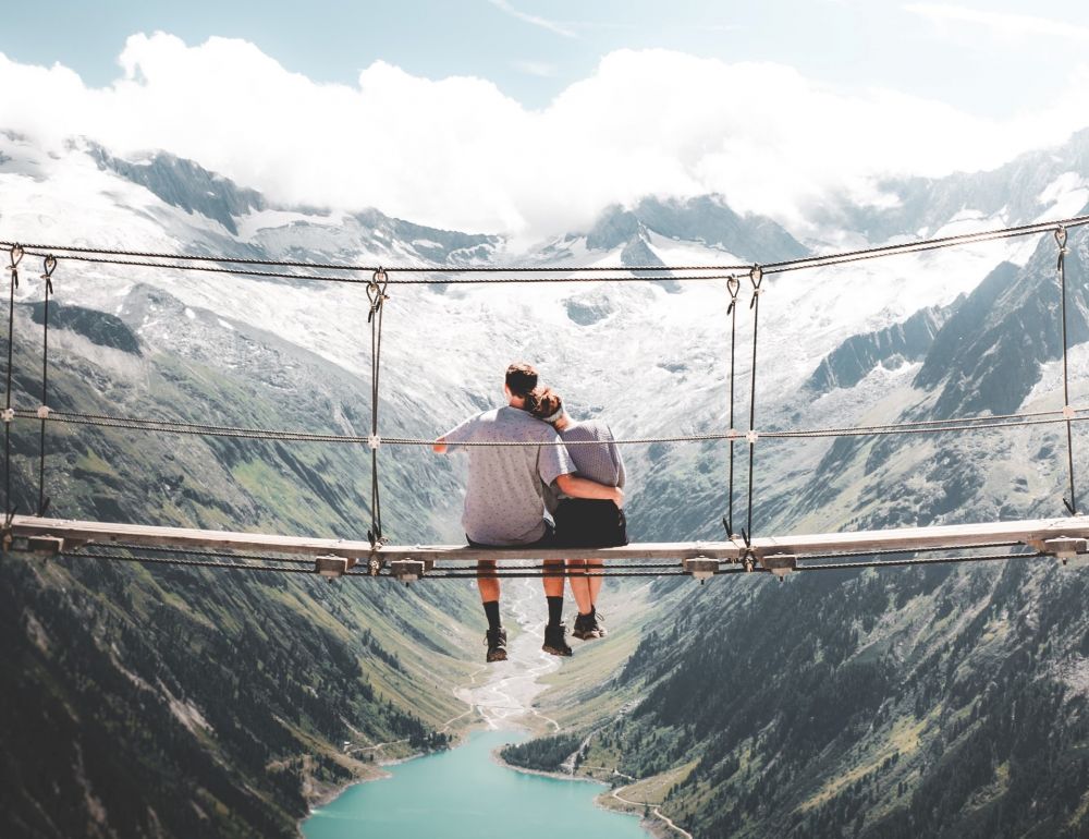 Couple-sitting-on-bridge