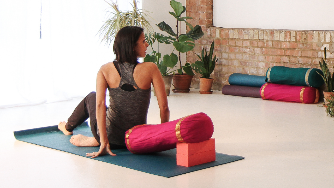 Mandy Jhamat, teaching an online class supported by a number of colourful yoga blocks and bolsters. Taken by Tom Cheater.